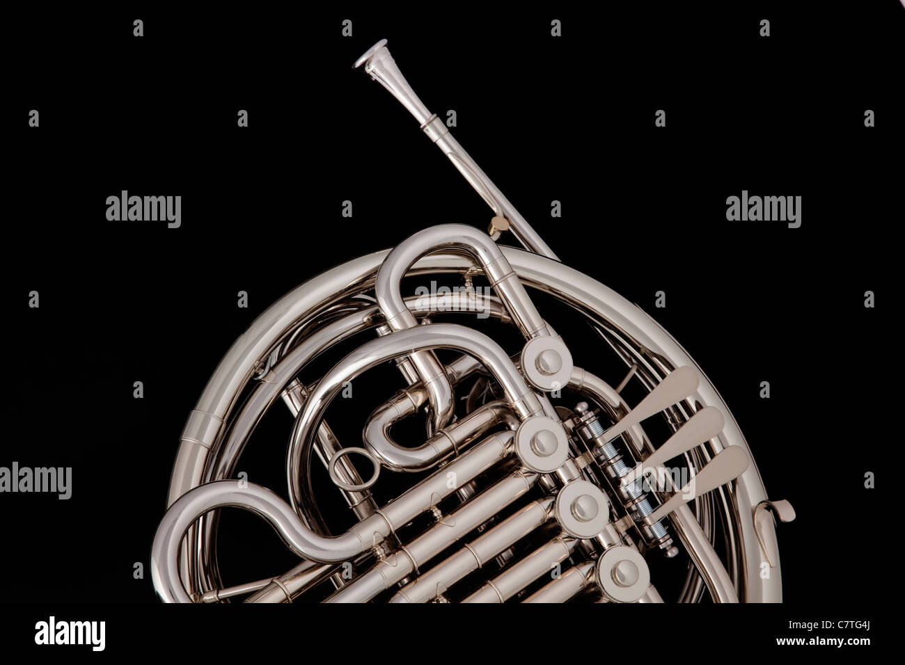 A silver professional French horn isolated against a black background