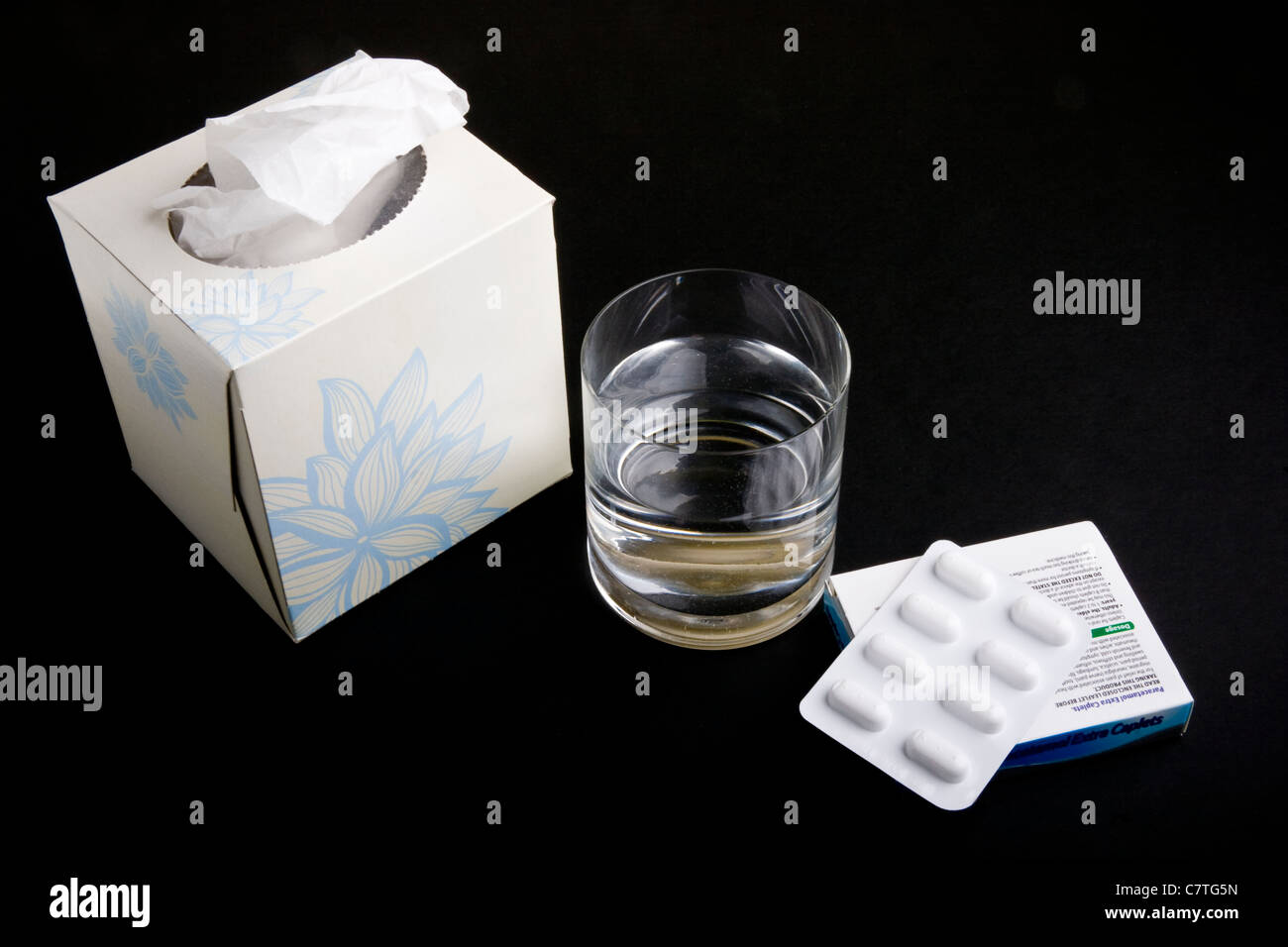 Sachet of tablets, glass of water and a box of tissues Stock Photo
