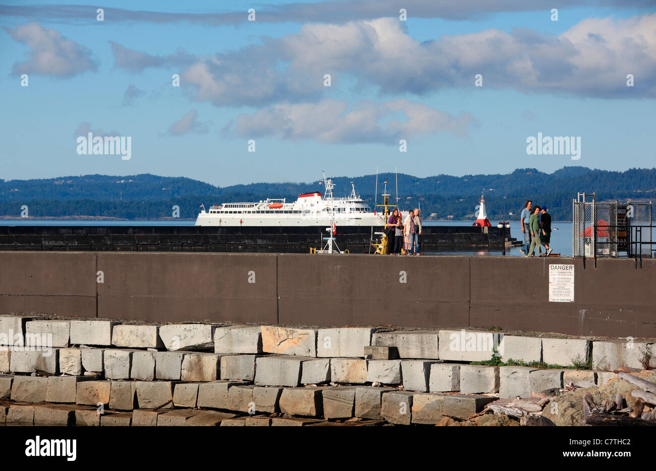 Coho ferry coming into Victoria harbour from port angeles. Ogden point breakwater with people walking along. Stock Photo