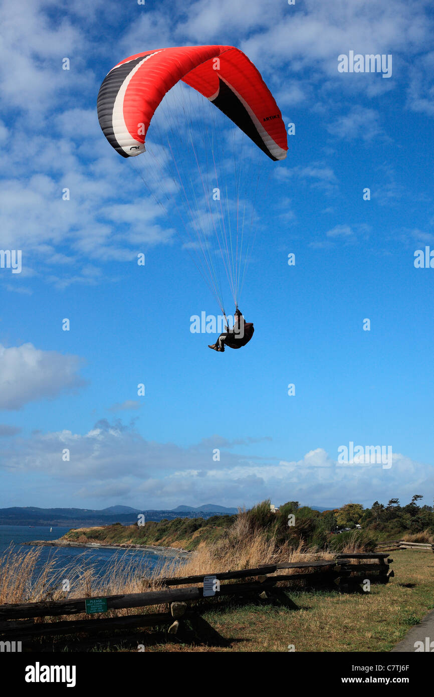 Man paragliding over cliff  by the ocean Stock Photo