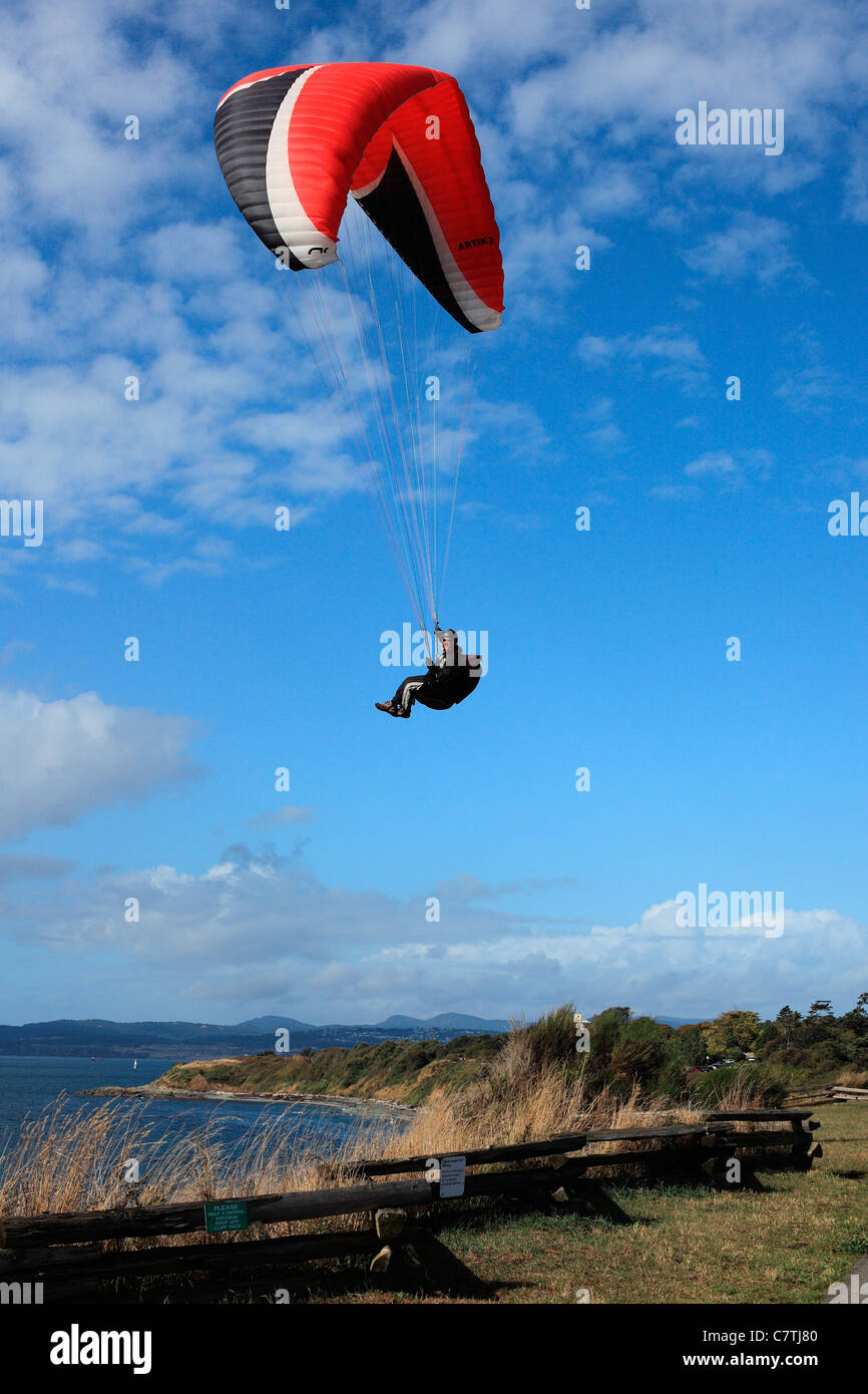 Man paragliding over cliff  by the ocean Stock Photo