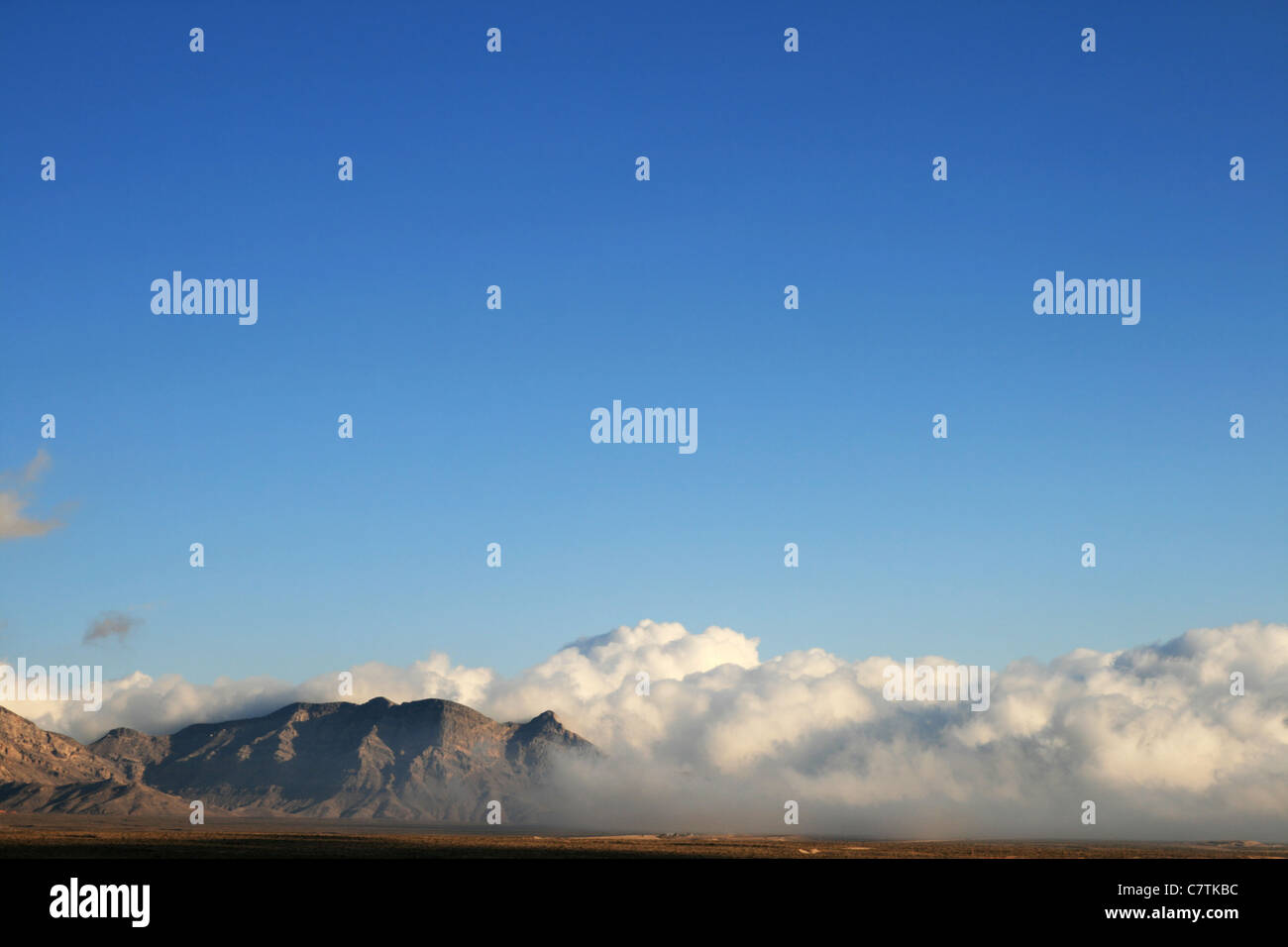 dramatic storm clouds around a desert mountain with blue sky copy space above Stock Photo