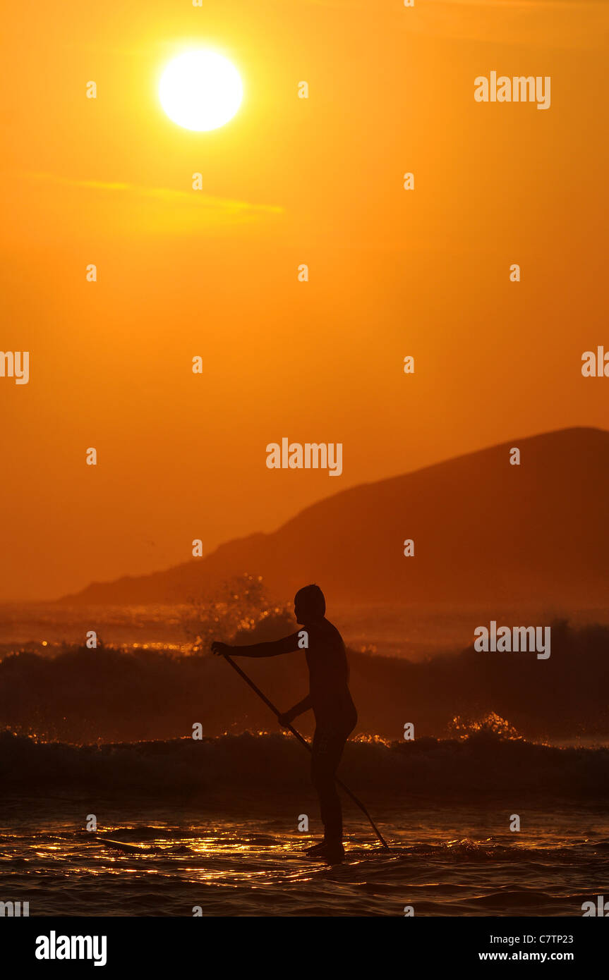 A paddle boarder enjoys the sunset of Bantham Beach in Devon, as the