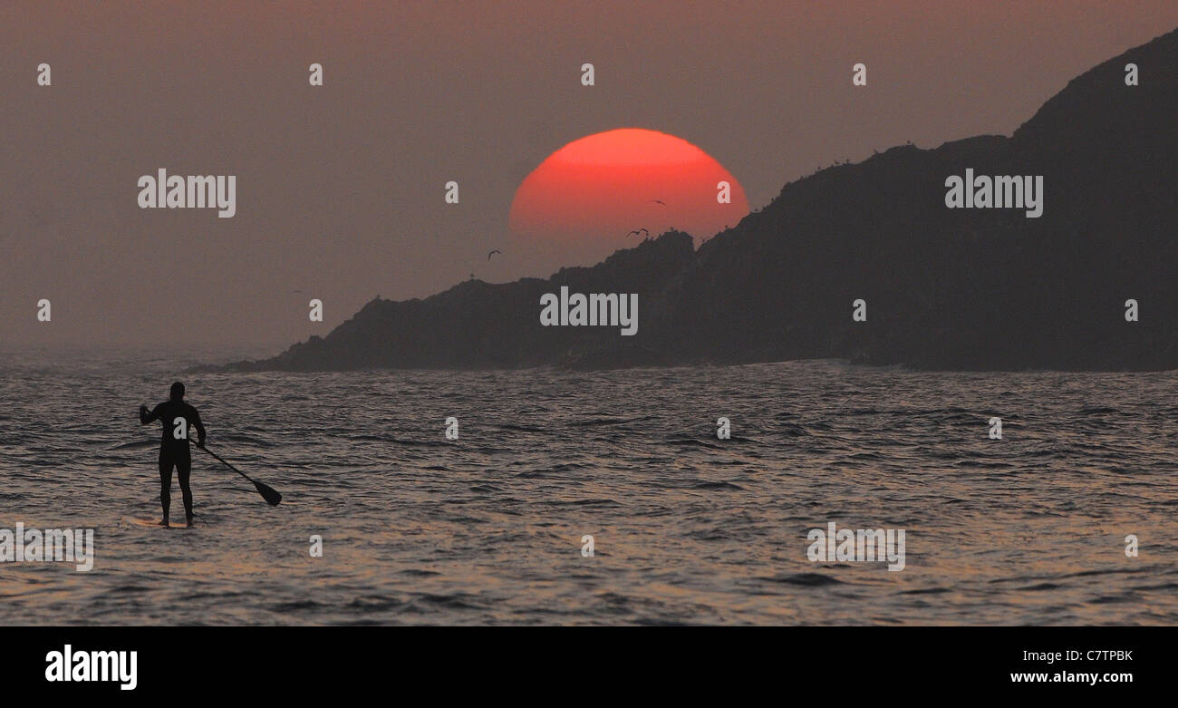 A paddle boarder enjoys the sunset of Bantham Beach in Devon, as the