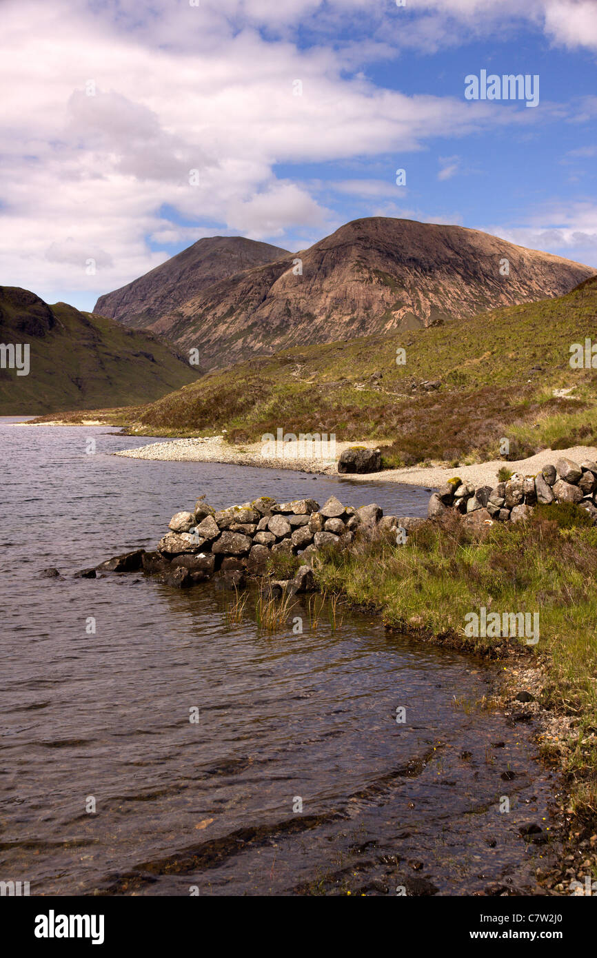 Old wall and sandy shoreline of Loch na Creitheach with Red Cuillin mountains in the distance, Isle of Skye, Scotland, UK Stock Photo