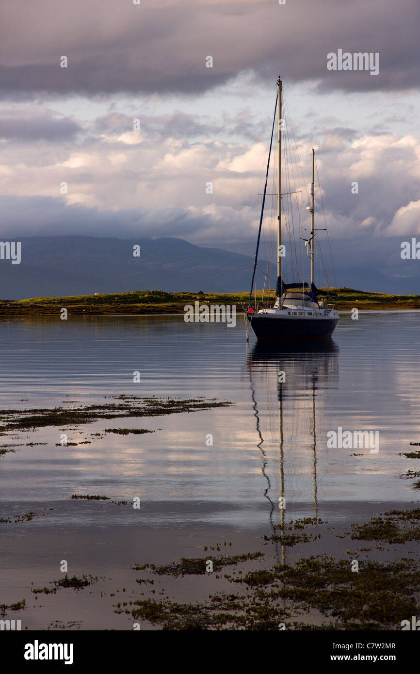 Moored sailing yacht in sea inlet at Lower Breakish on the Isle of Skye with Scottish hills in the distance, Scotland, UK Stock Photo