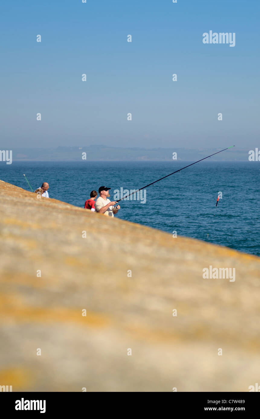Shallow focus shot of Anglers by harbour wall Mevagissey Cornwall UK Stock Photo