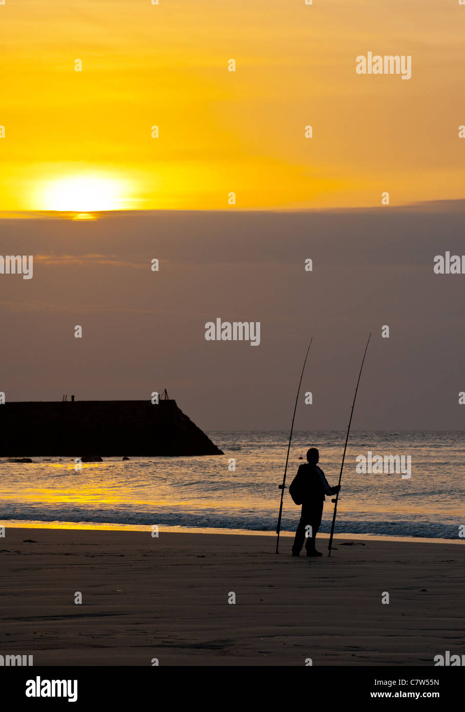 An angler on Sennen beach at sunset. Stock Photo