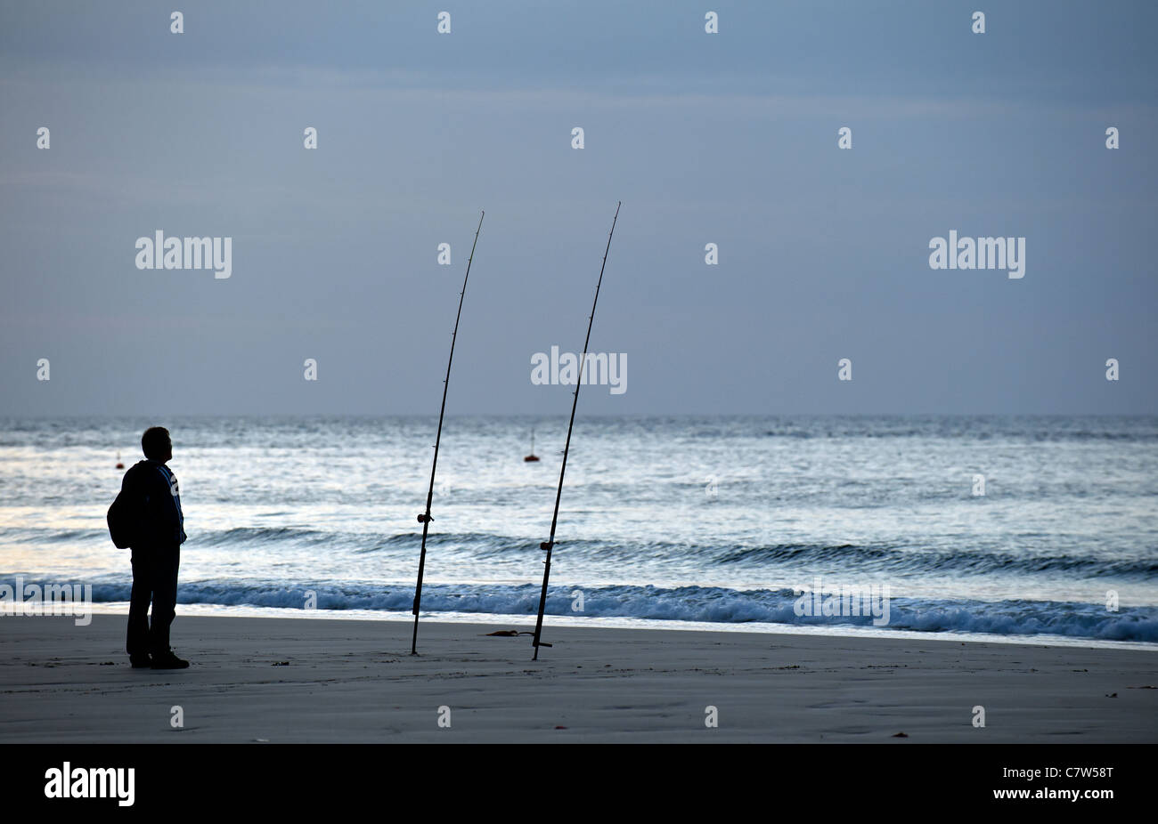 An angler on Sennen beach at dusk Stock Photo