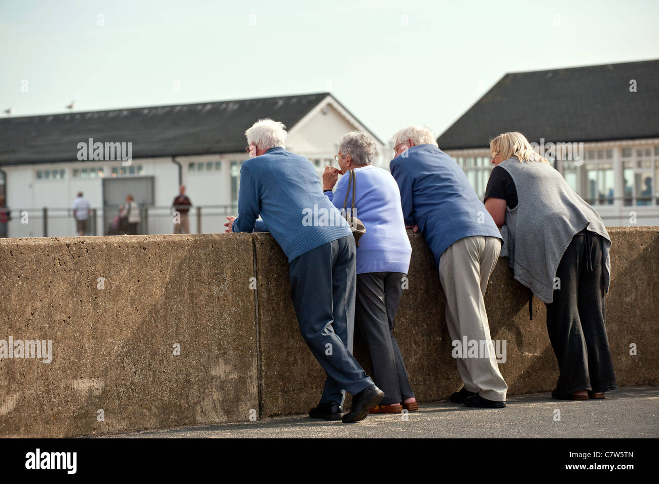 Tourists leaning on a wall on the coast at Southwold in Suffolk Stock Photo