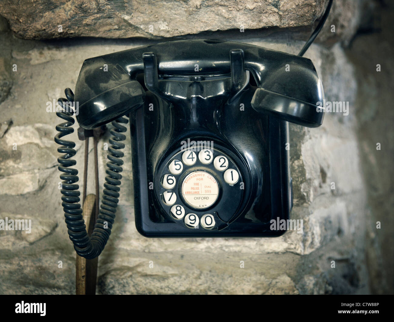 black vintage telephone wall mounted on stone wall Stock Photo