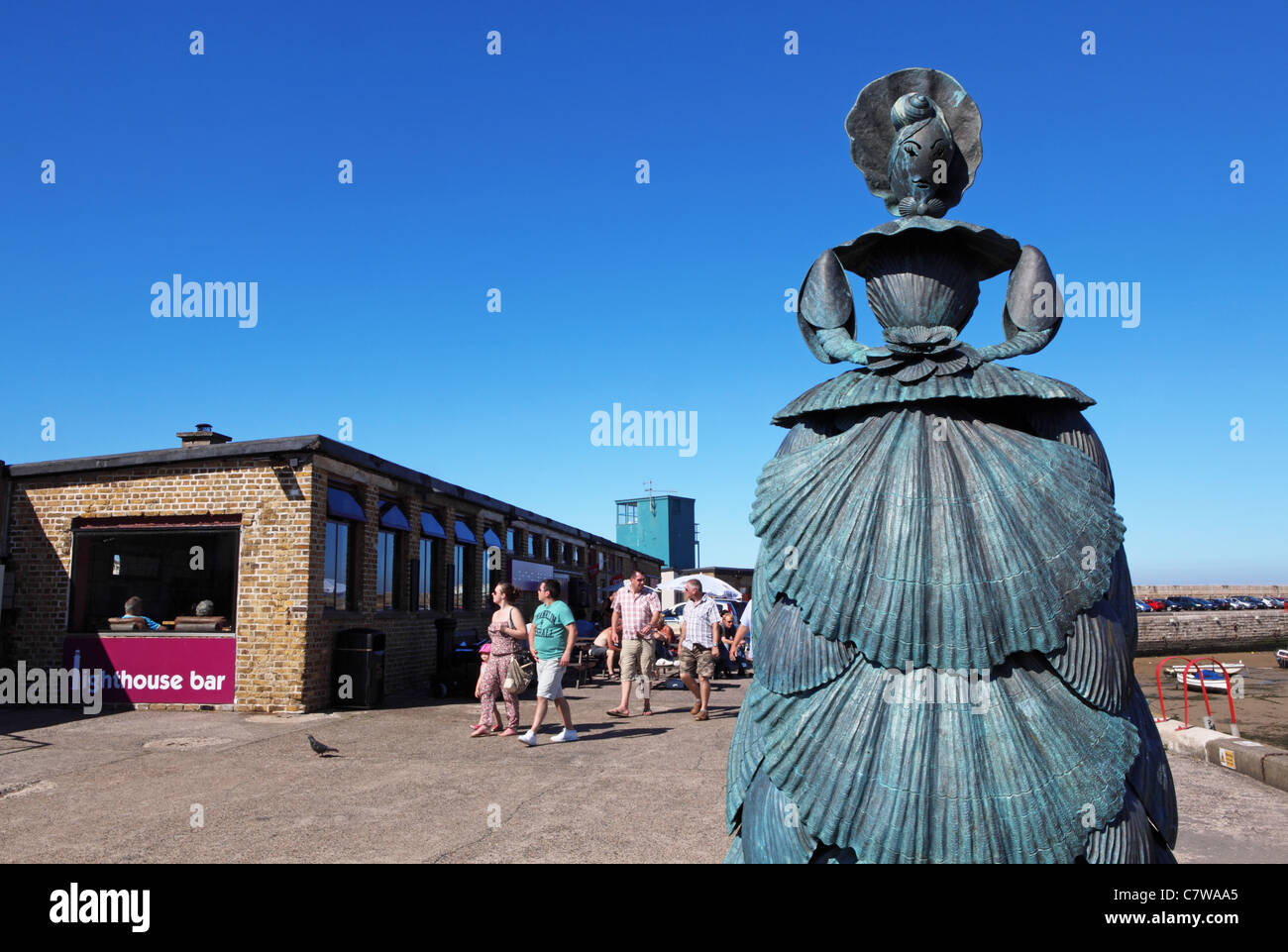 Statue of Mrs Booth, the shell lady of Margate, by Anne Carrington, on the Harbour Arm, Lighthouse Bar behind, in Margate, Kent Stock Photo