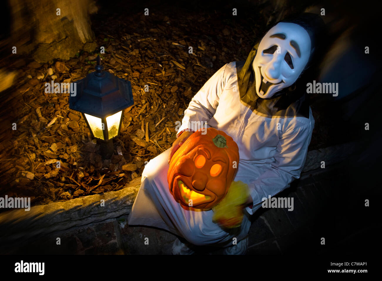 Person in Halloween costume holding pumpkin Stock Photo