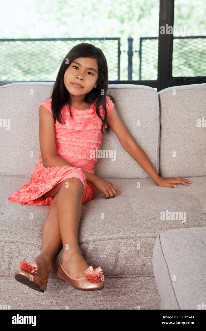 young girl sitting on couch in a dress Stock Photo