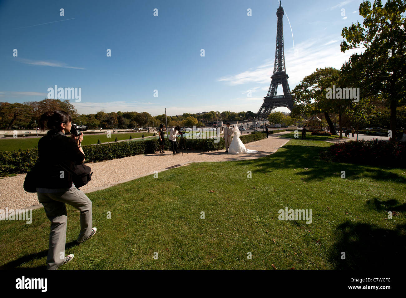 Bride and Groom from Japan pose for their wedding photographs below the Eiffel Tower, Paris France. Stock Photo
