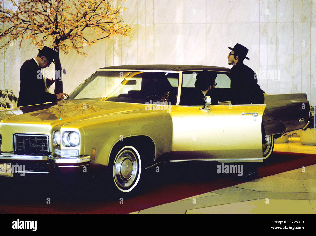 Two men inspect a 1970's car in a Fifth Ave Showroom New York USA Stock Photo