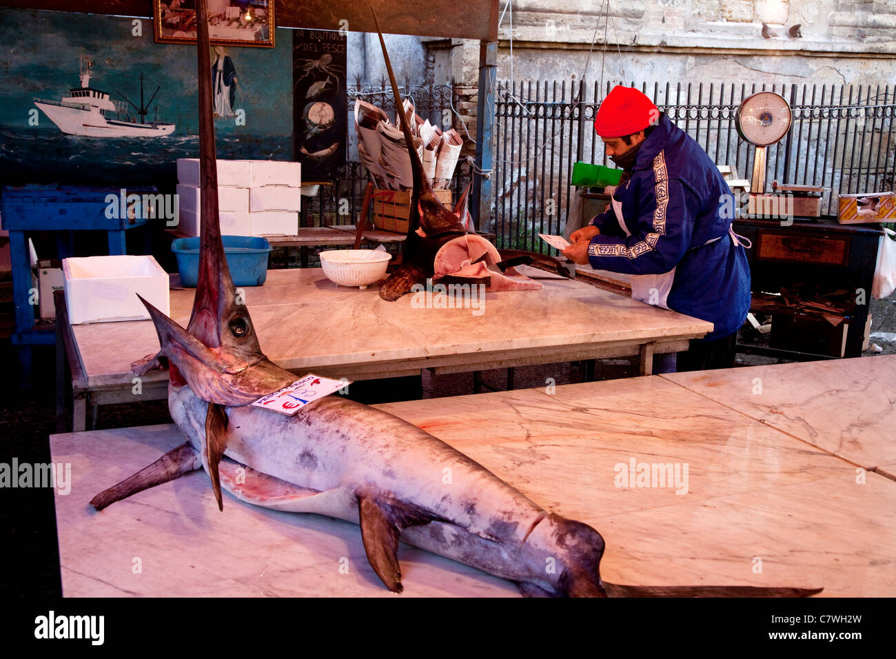 Man cutting slices of swordfish, traditional fish shop selling seafood