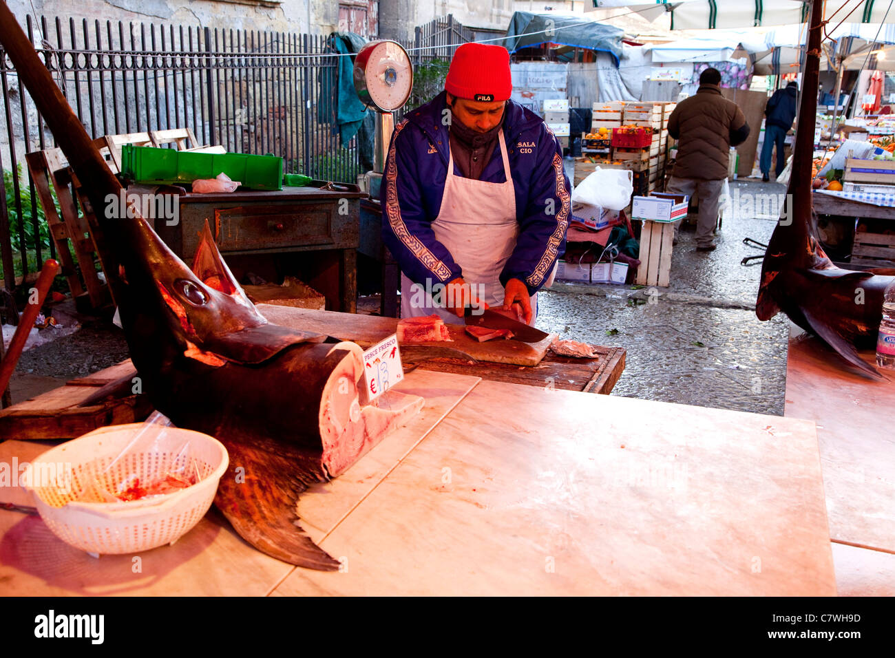 Man cutting slices of swordfish, traditional fish shop selling seafood