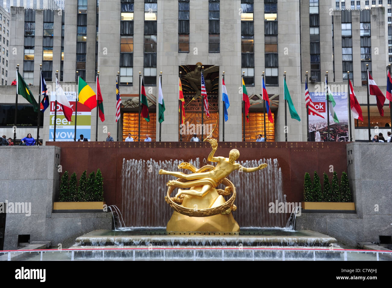 View, towards people and flags, gilded sculpture Prometheus, front GE Building, Rockefeller Centre Ice Rink, New York City, USA Stock Photo