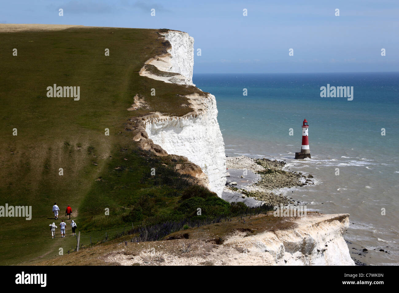 Hikers walking along South Downs Way coast path, Beachy Head lighthouse ...