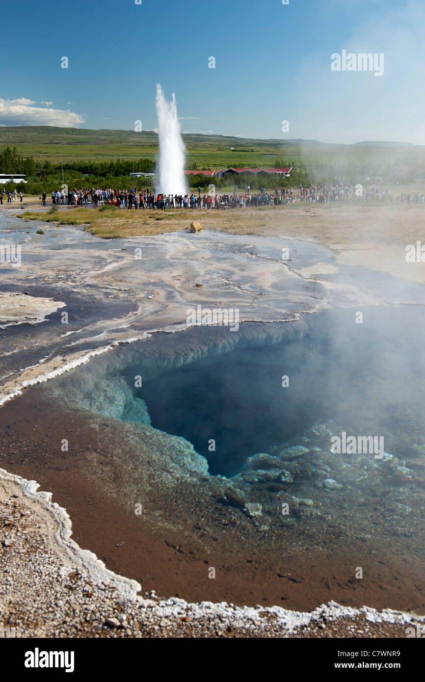 Thermal pools at Geysir in southwest Iceland. Strokkur geyser can be seen erupting in the background. Stock Photo