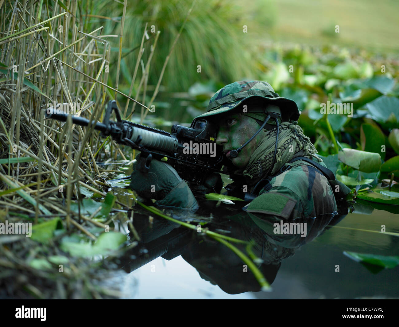 U.S. Navy SEAL crosses through a stream during combat operations. Stock Photo