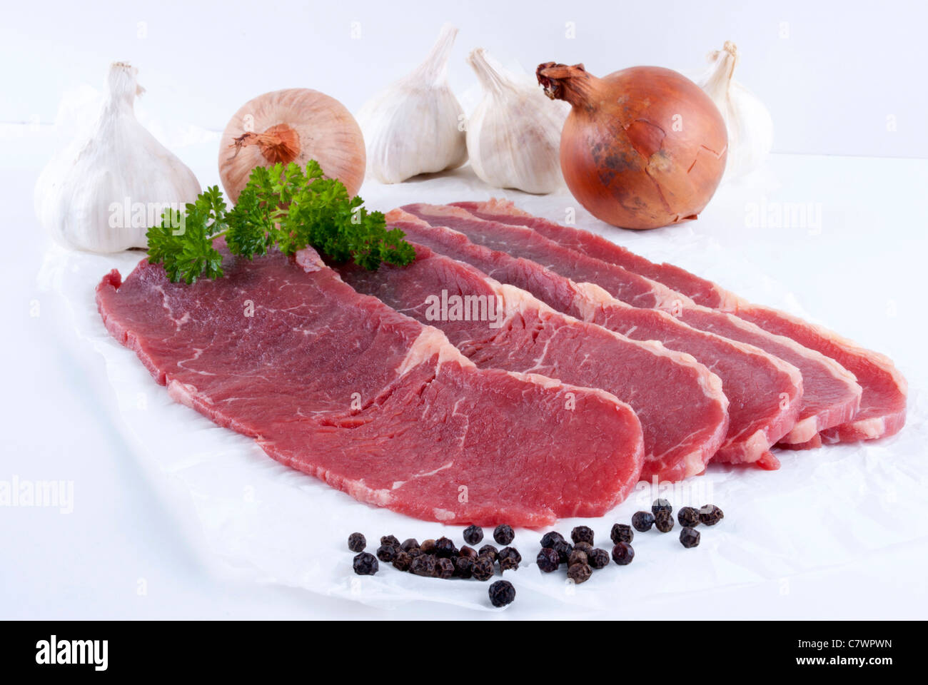 thin cut beef steaks with garlic and onions Stock Photo Alamy