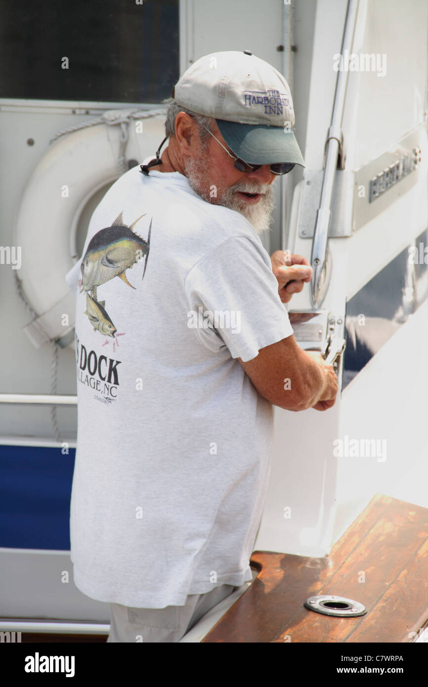 boat captain docking boat at town dock to pickup passengers Stock Photo