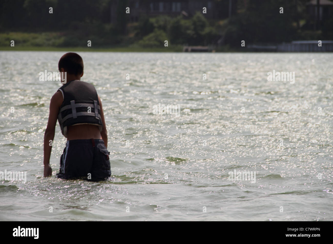 sandbar walking through water Hispanic boy bathing suit lake Stock Photo
