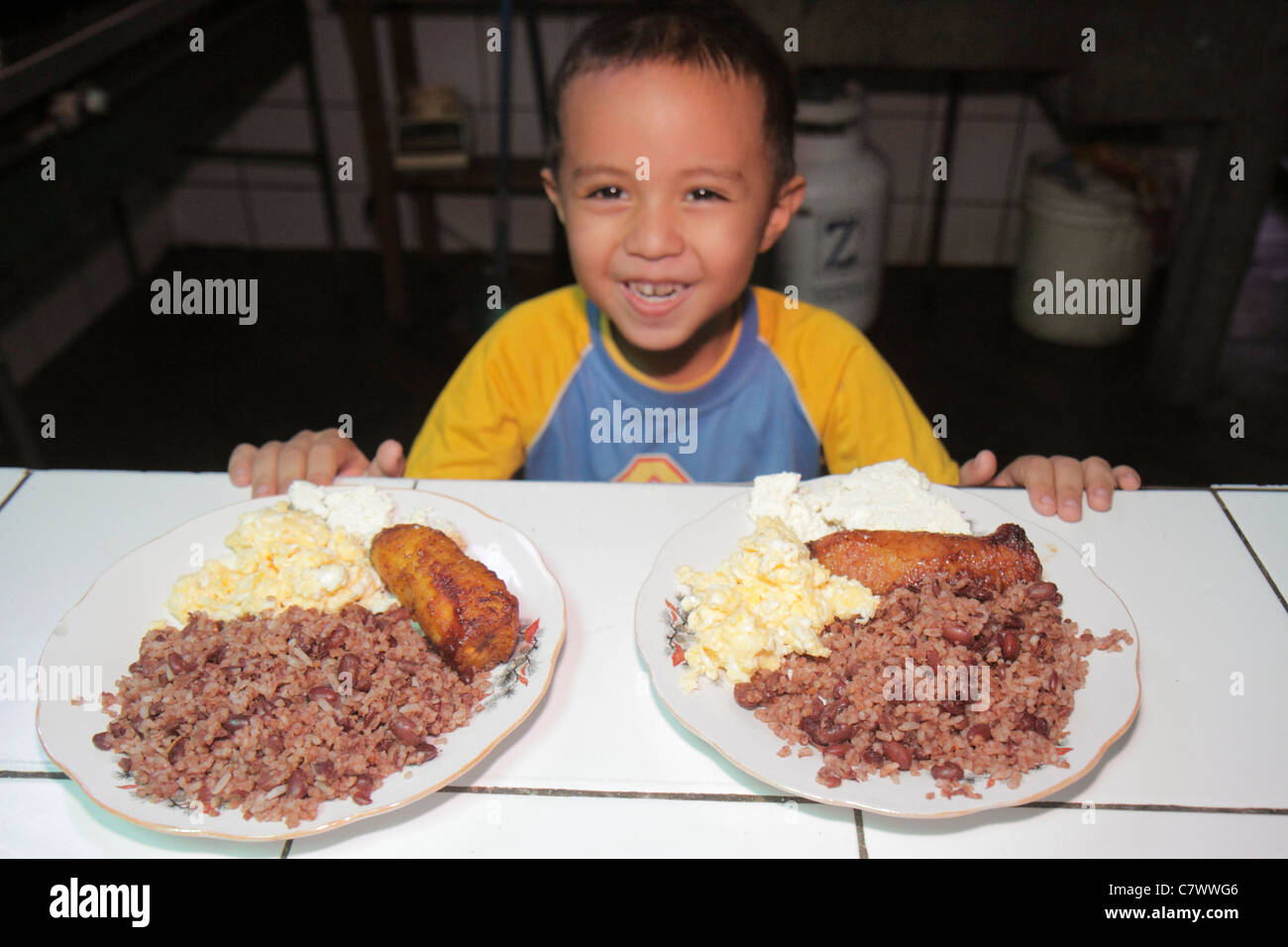 Managua Nicaragua,Hispanic boy boys,male kid kids child children youngster,preschooler,food,plate,dish,typical food,rice,beans,scrambled eggs,fried pl Stock Photo