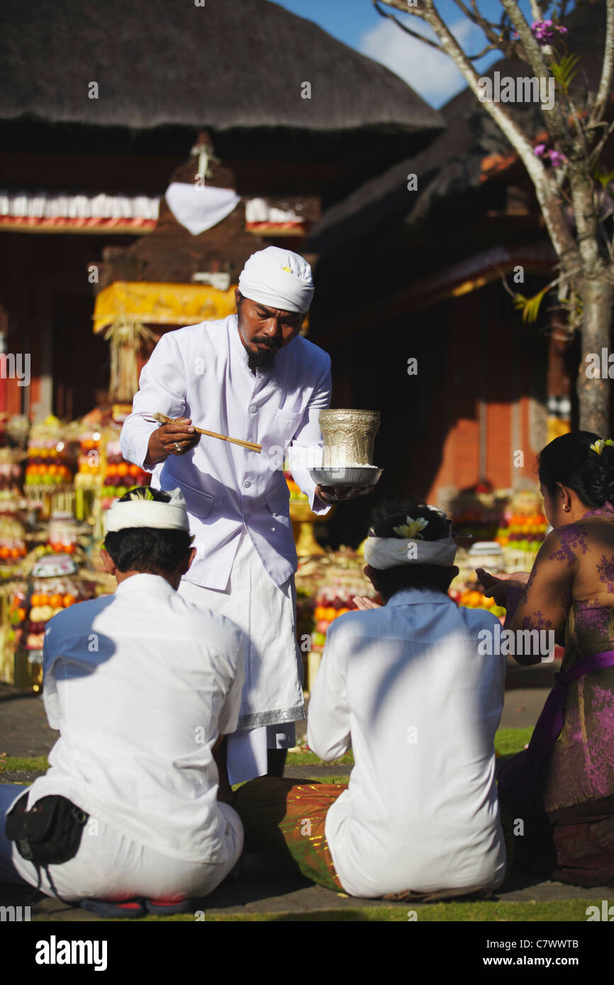 People receiving blessing from priest at temple ceremony, Bali