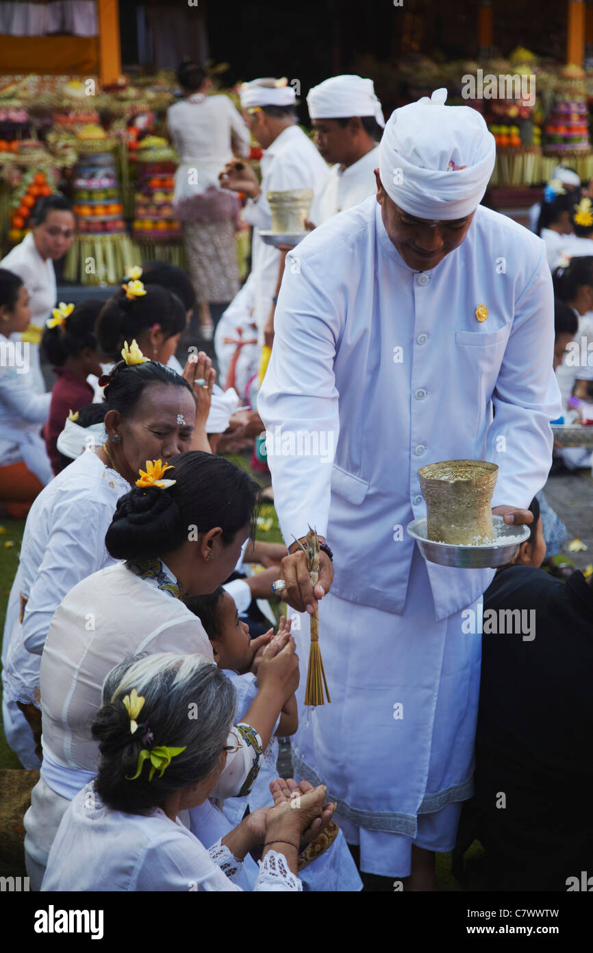 People receiving blessing from priest at temple ceremony, Bali