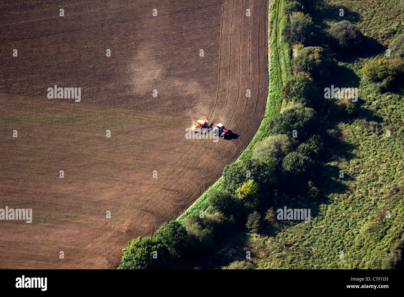 Aerial view of a single tractor in a dry field with dust billowing, tilling the dry soil, Stock Photo