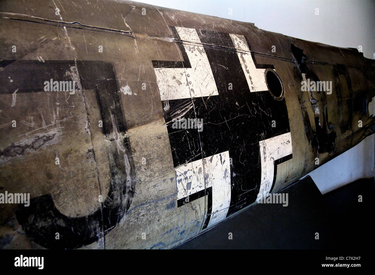 The Luftwaffe Balkenkreuz on the fuselage of a crashed German WW2 aircraft. Scratched and distressed markings cover the surface. Stock Photo