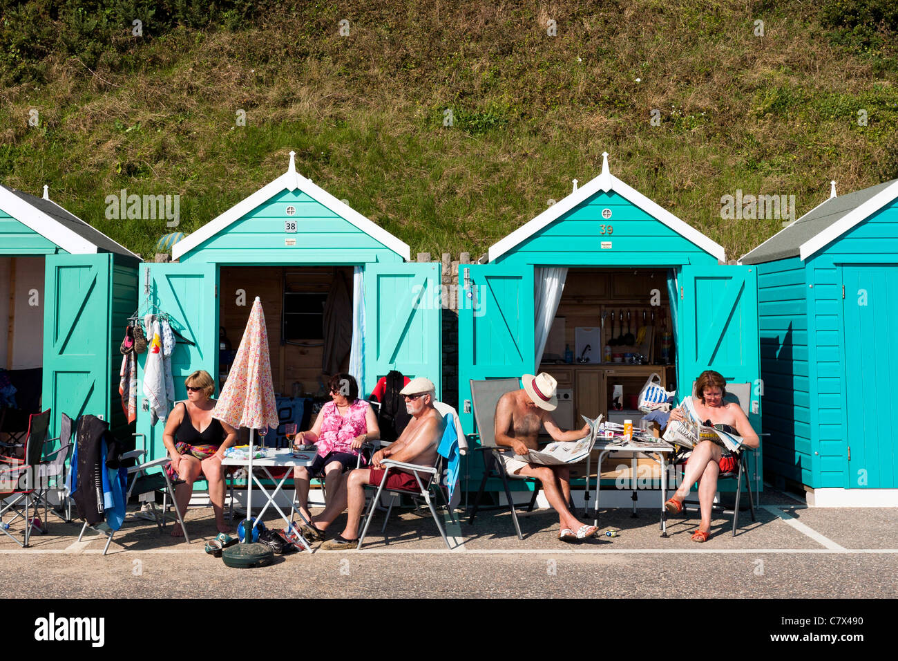 Members of the public relax outside beach huts. Stock Photo