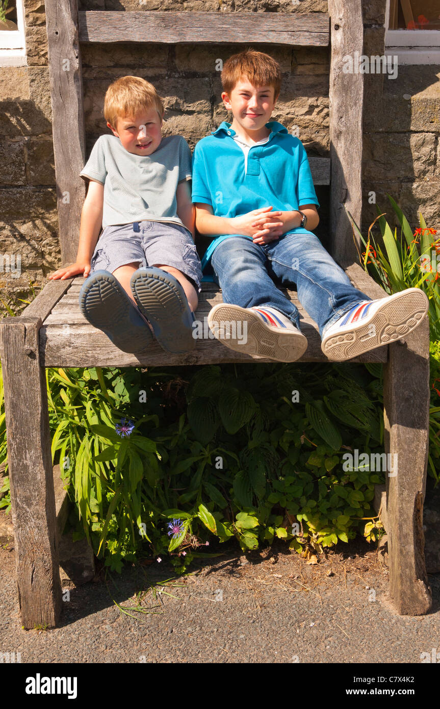 Two boys sit on the giant chair outside the Old School Crafts Shop at