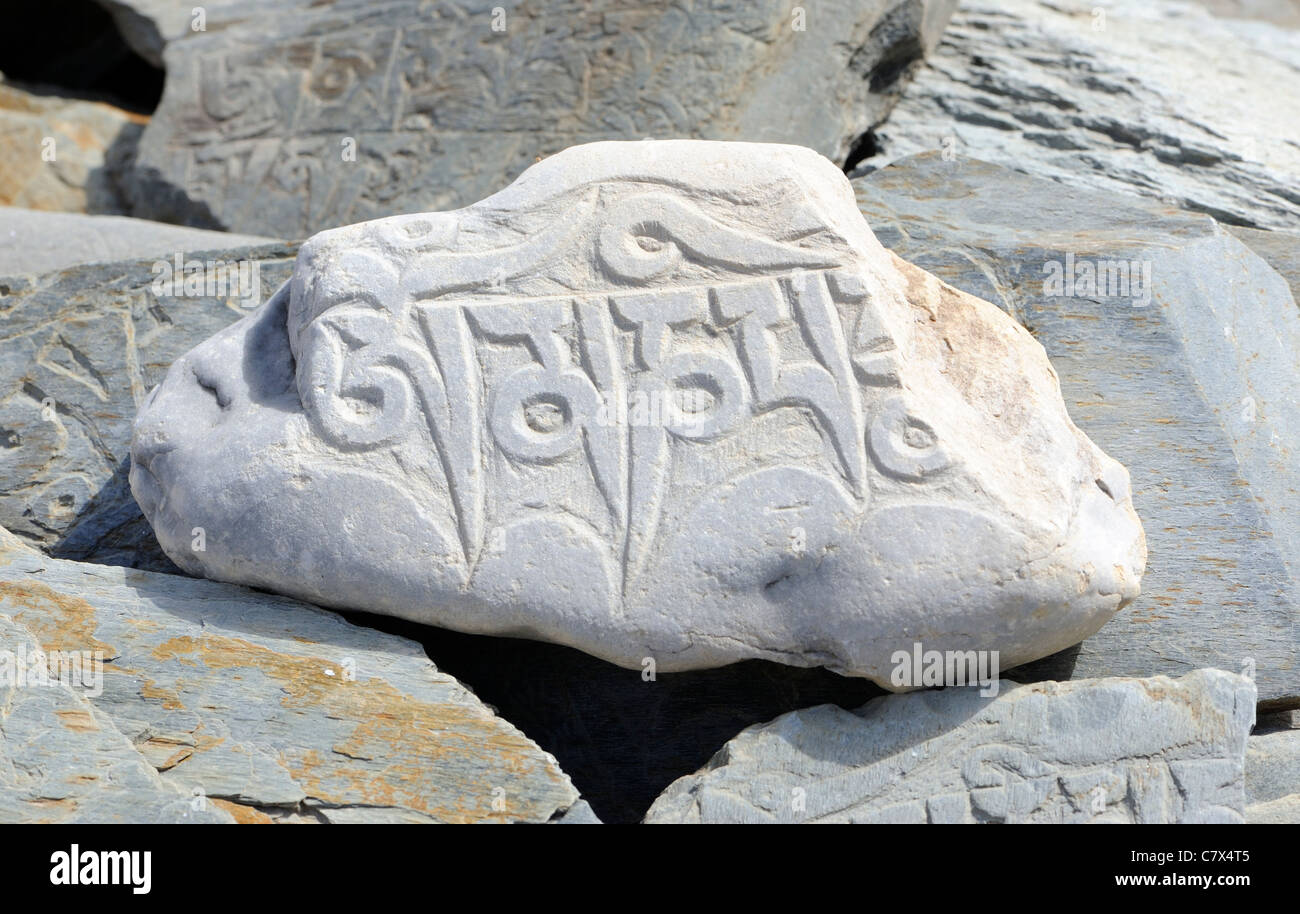 A river boulder carved with the mantra om mani padme hum on a prayer wall. Rangdum, Zanskar , Ladakh. Stock Photo