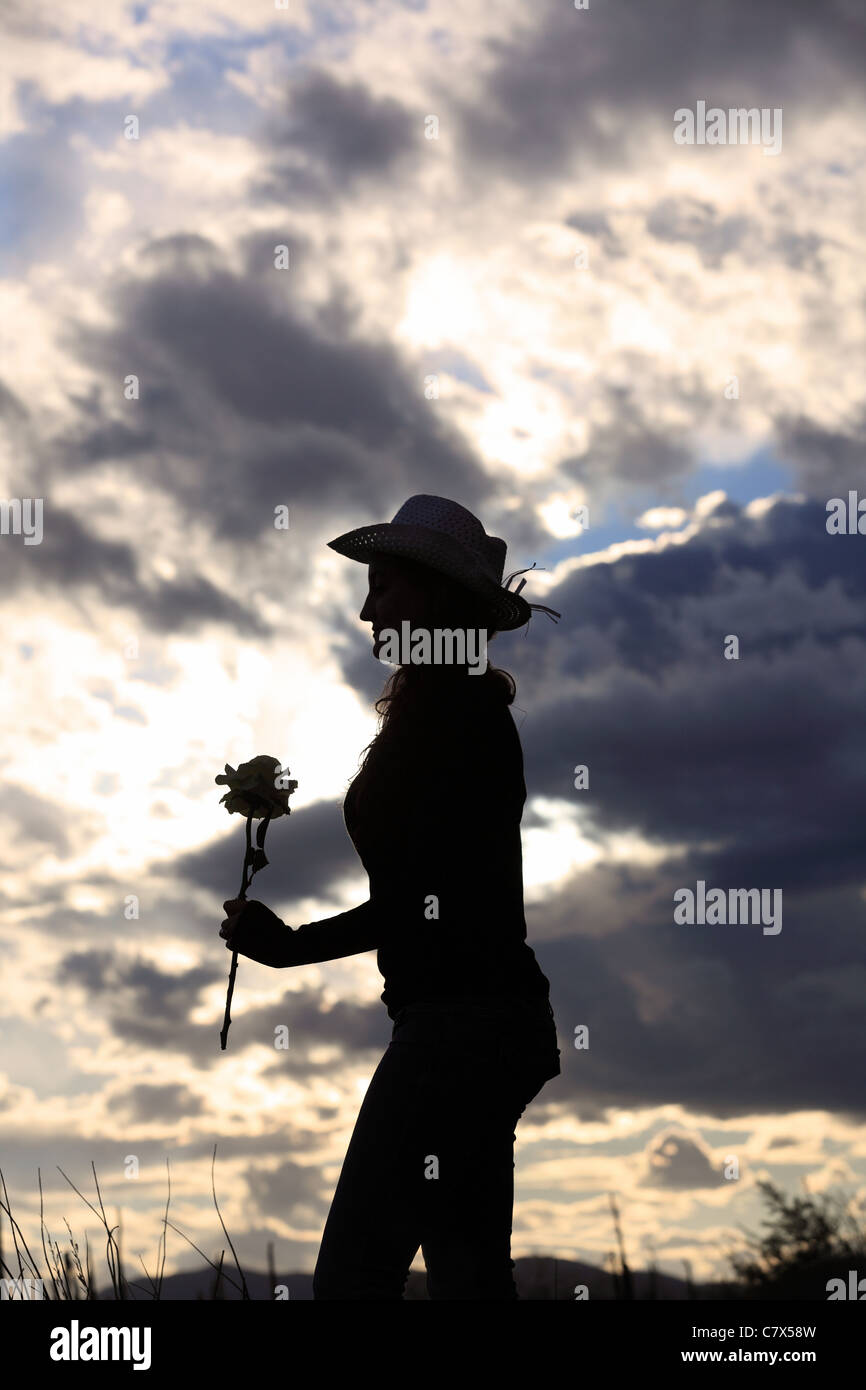 The silhouette of a woman in a cowboy hat holding a rose Stock Photo ...