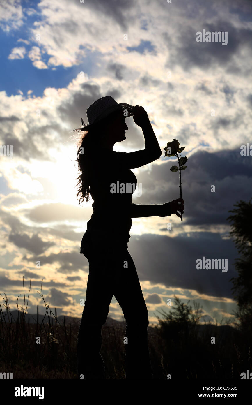 The silhouette of a woman in a cowboy hat holding a rose Stock Photo ...