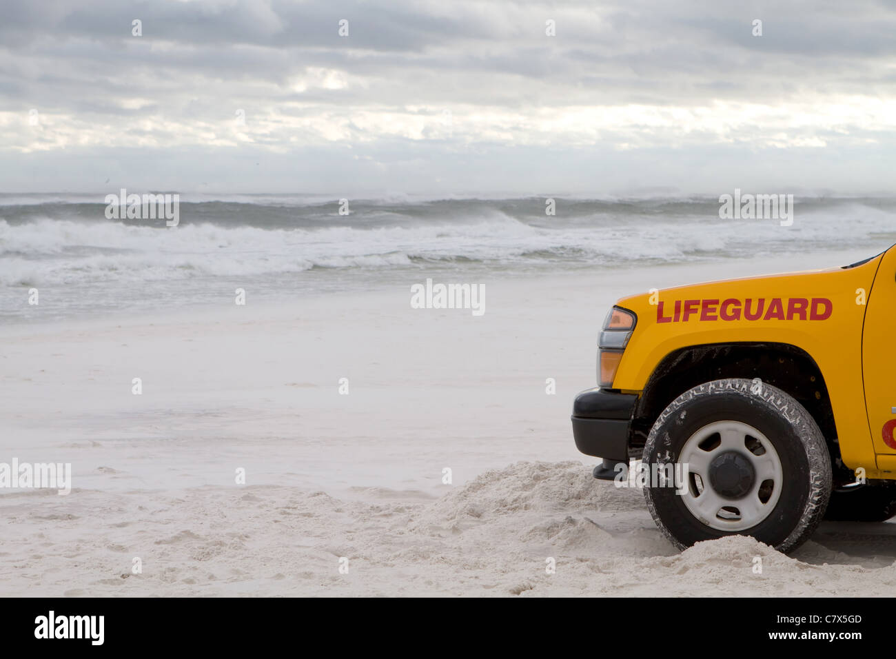 Lifeguard truck is parked on the beach as tropical storm generated waves come ashore to warn swimmers about the dangerous surf. Stock Photo
