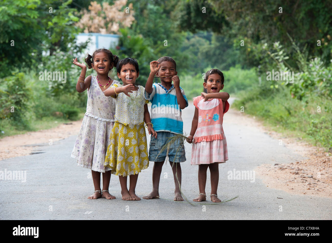 Happy young rural Indian village children standing on a road laughing waving and smiling. Andhra Pradesh, India Stock Photo