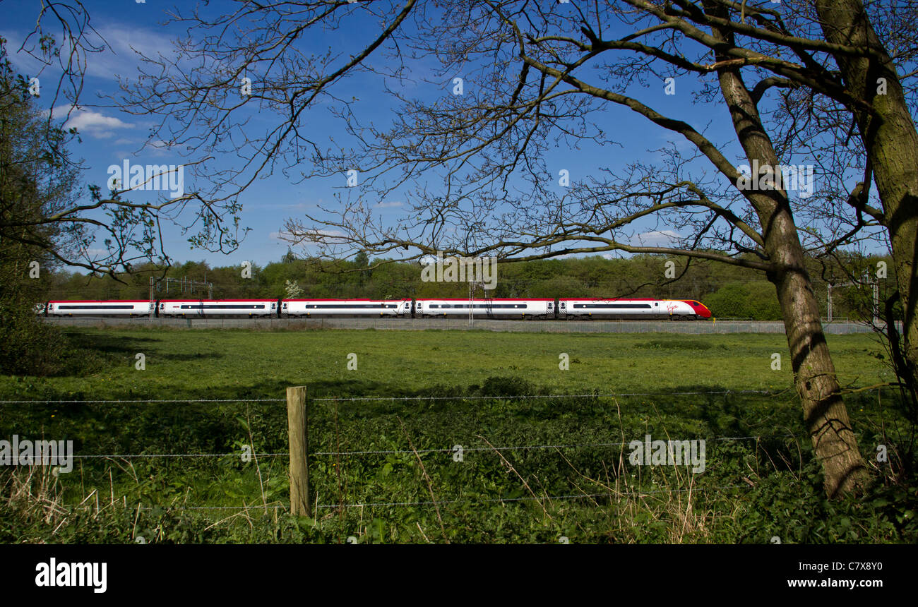 A Virgin Train class 390 Pendolino passing Slindon, Mill Meece, Staffordshire. 3rd May 2011 Stock Photo