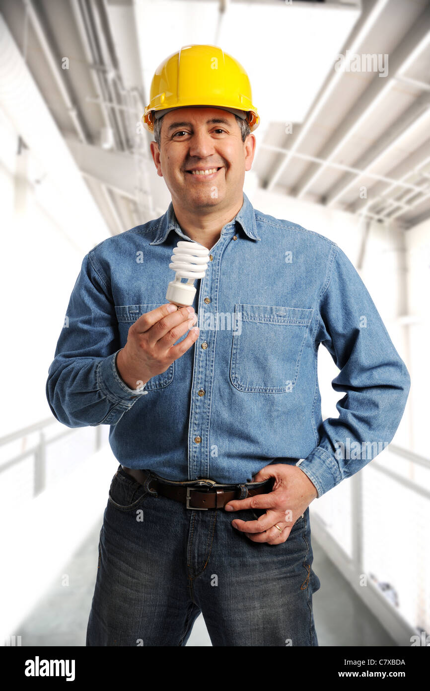 Engineer holding an electrical bulb and wearing a hard hat inside a