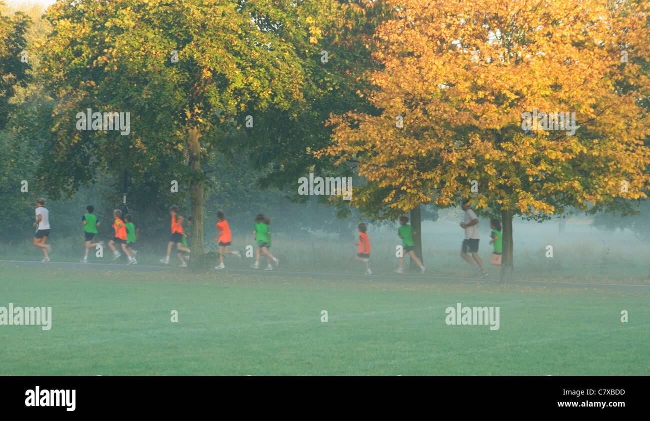 School children running on misty morning, Wandsworth Common, London UK Stock Photo