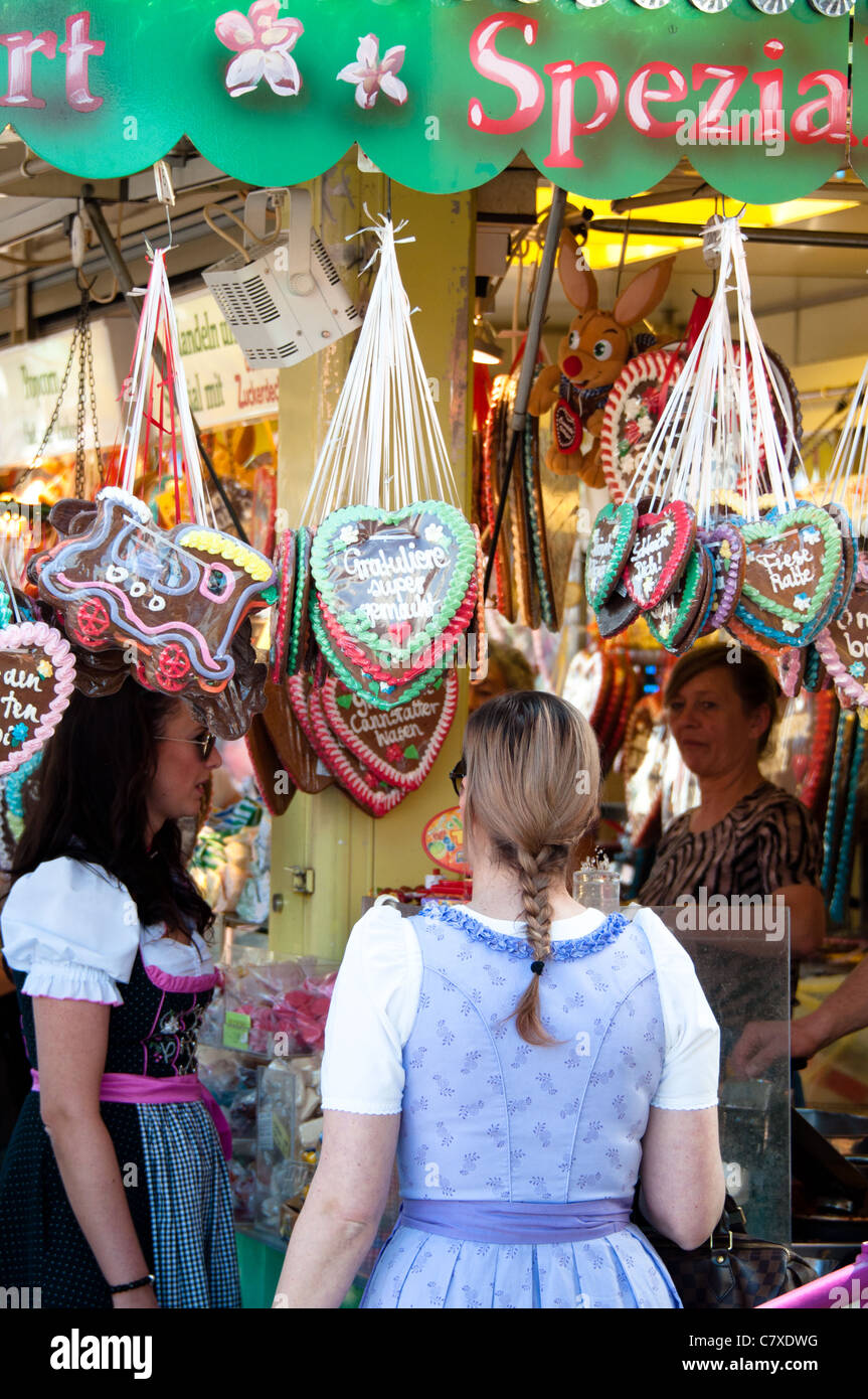 Young girls in traditional German costume (Dirndl) about to buy a traditional Gingerbread heart at the Cannstatter Wasen Stock Photo