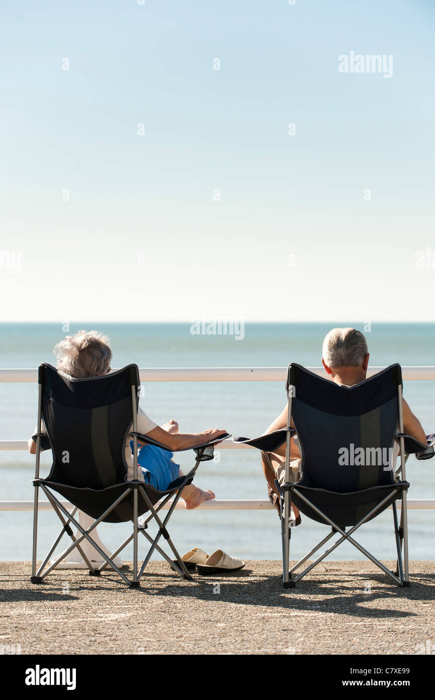 a man woman senior couple sitting in canvas folding chairs enjoying the late september 2011 heatwave, aberystwyth wales uk Stock Photo