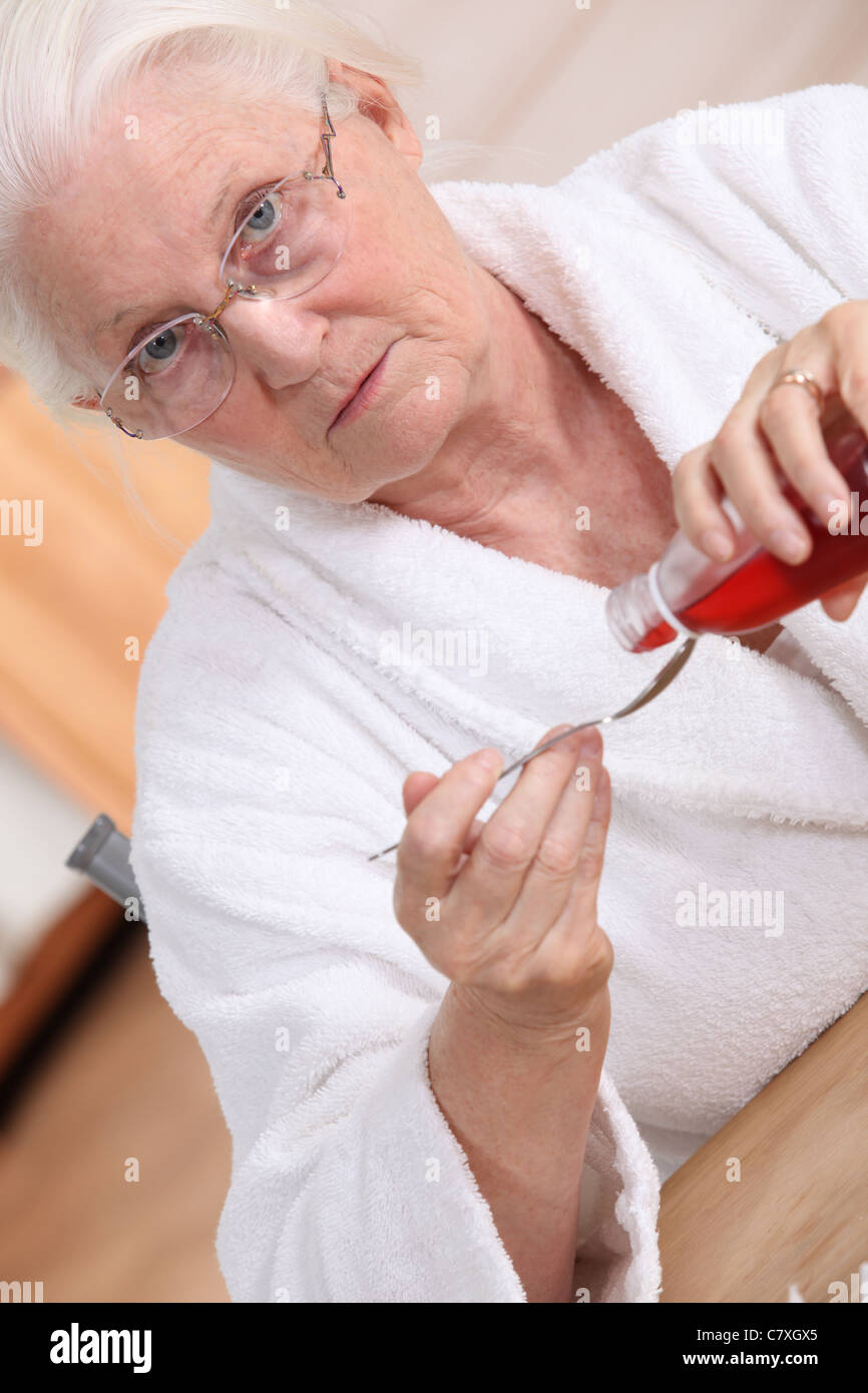 Old woman drinking cough syrup Stock Photo Alamy