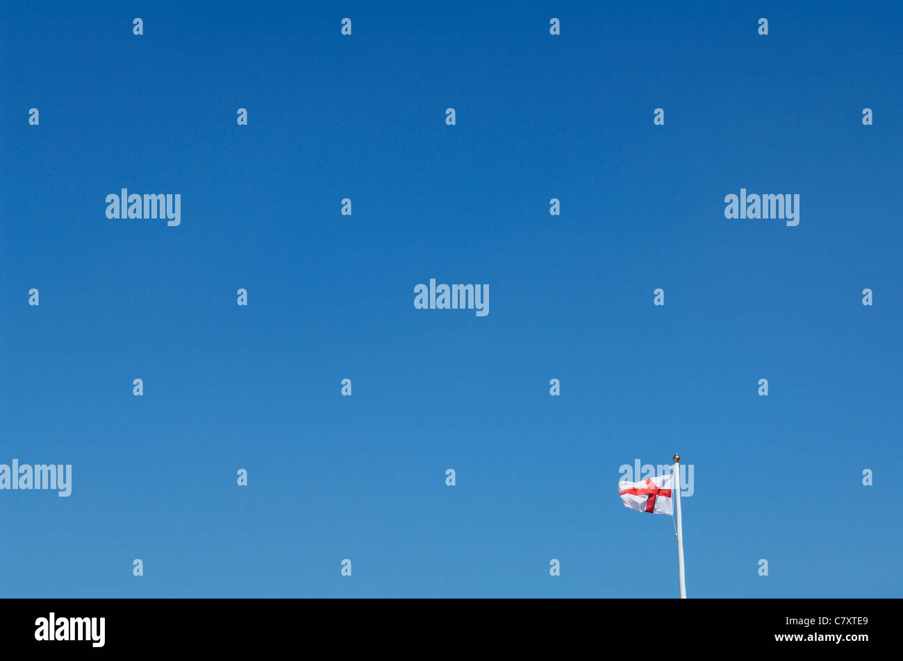 A distant St Georges Cross Flag of England against a clear blue sky. Stock Photo