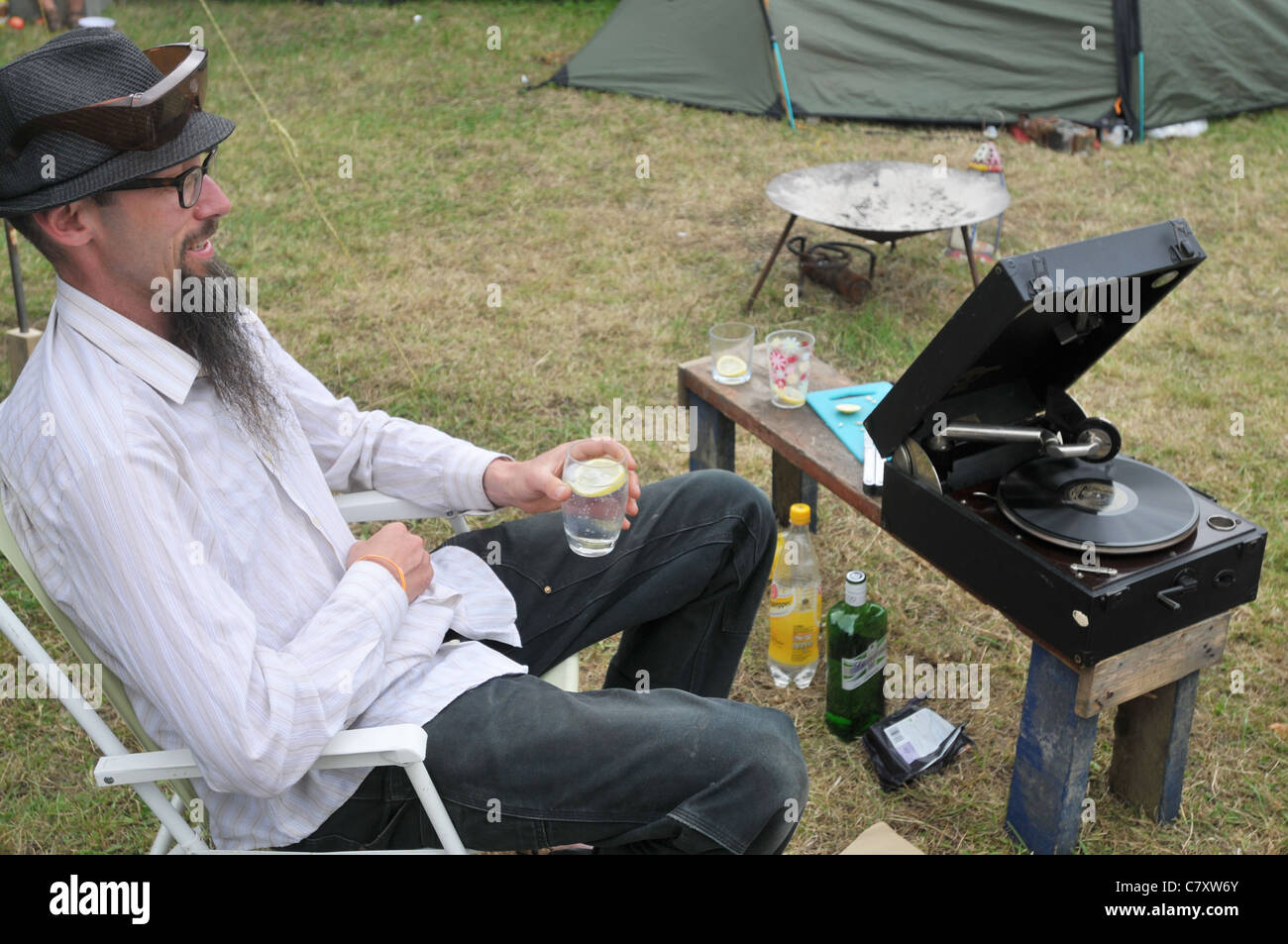 A middle-aged man at a UK festival listens to his 78 RPM gramophone whilst drinking a gin & tonic Stock Photo