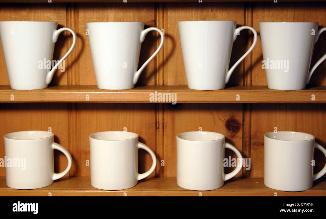 White mugs displayed on wooden shelves Stock Photo